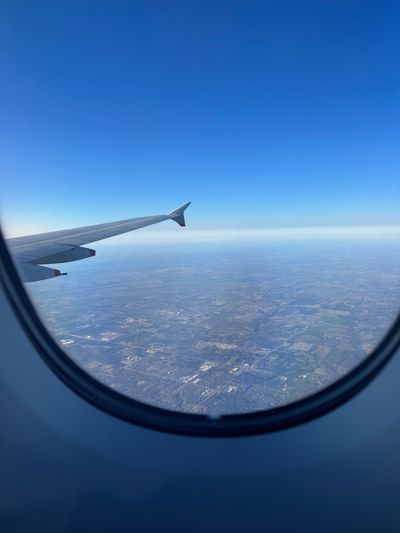 The view from an airplane window — a wing over patchwork land far below